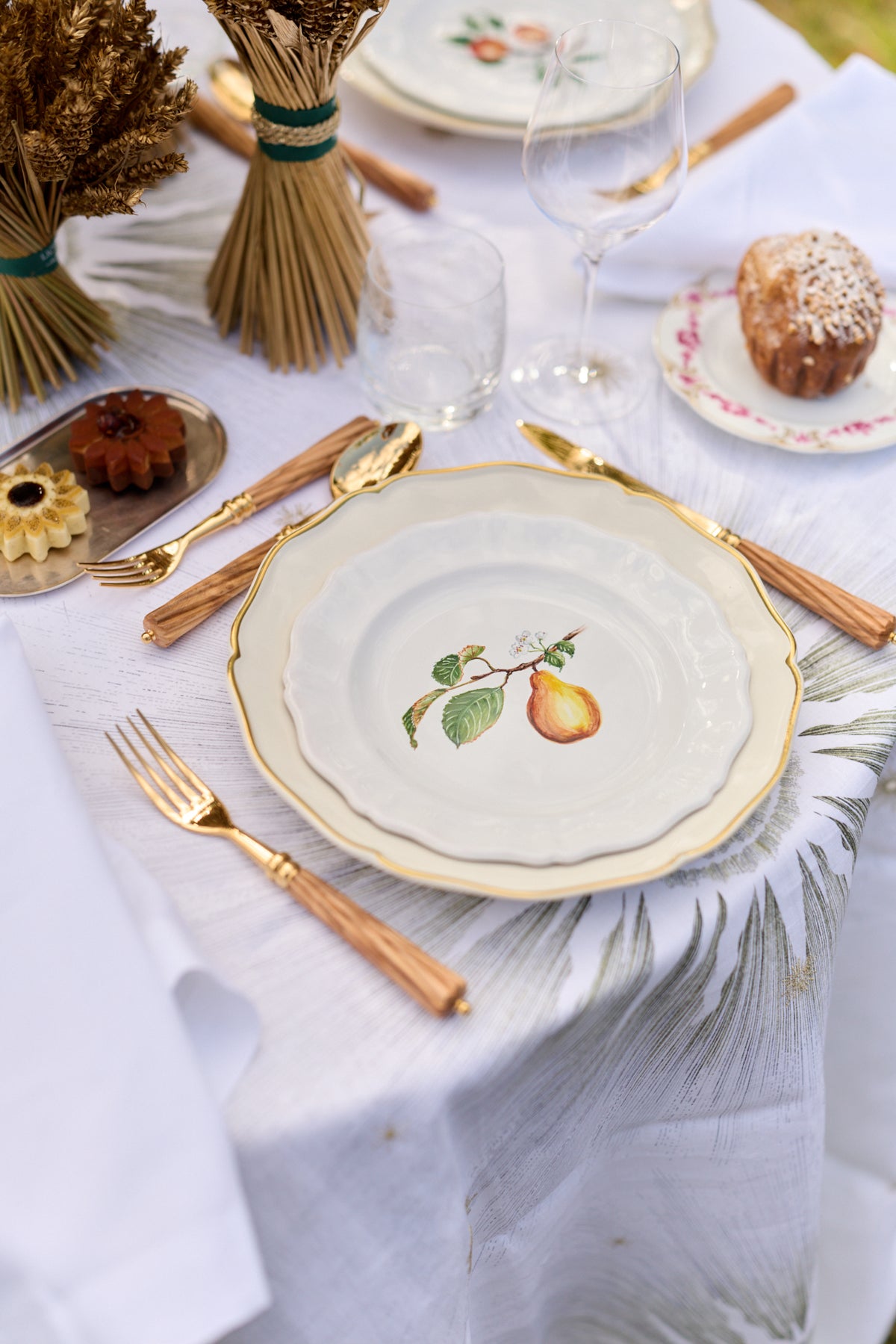 A Z.d.G. hand-painted pear plate styled on a white linen table setting with gold flatware.