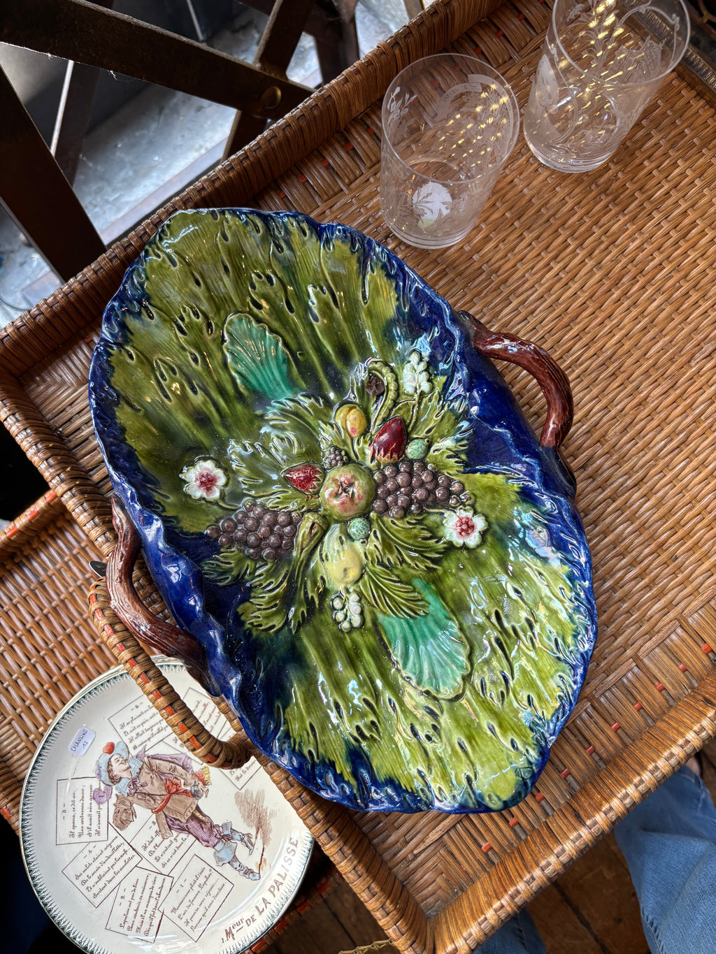 Decorative ceramic platter with floral design on a wicker table.