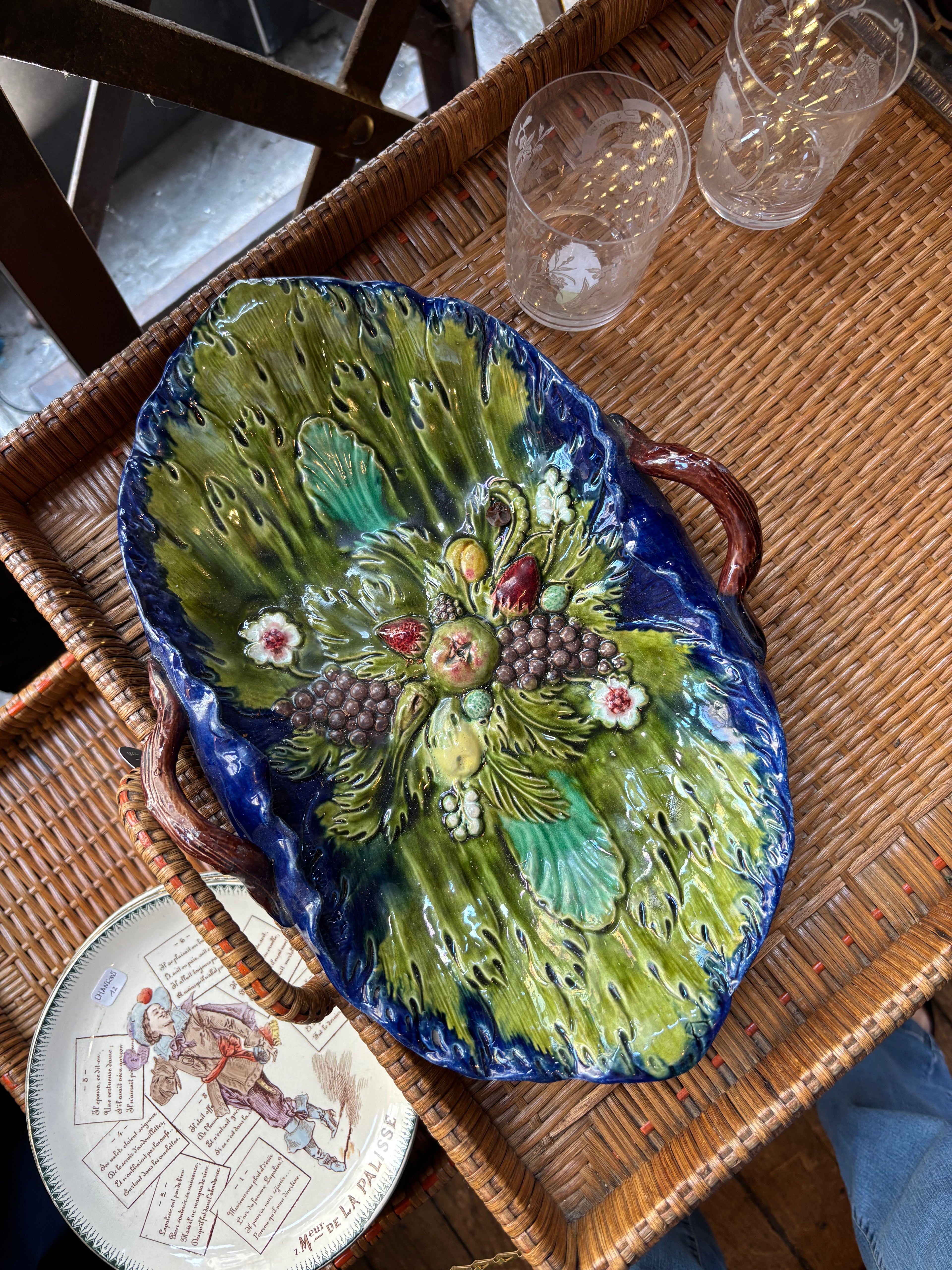 Decorative ceramic platter with floral design on a wicker table.