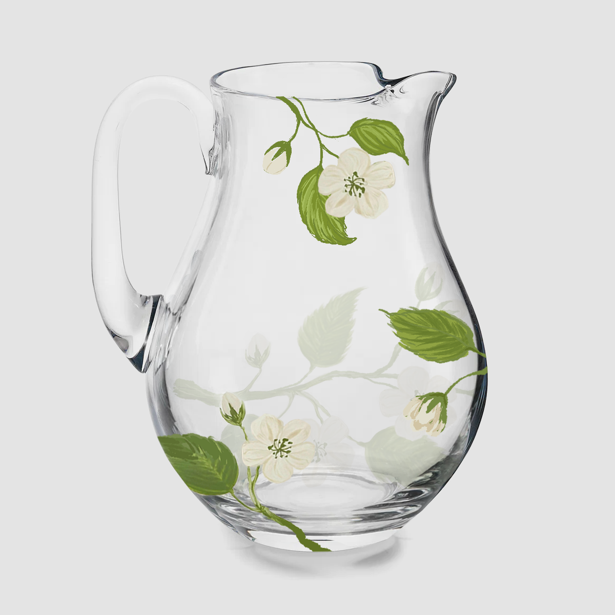 A product photograph of a clear glass pitcher with an elegant, curved silhouette and a wide pouring spout. The glass is delicately hand-painted with a botanical design featuring a slender branch with bright green leaves and a single, detailed green apple. The jug is shown empty against a clean, neutral background.