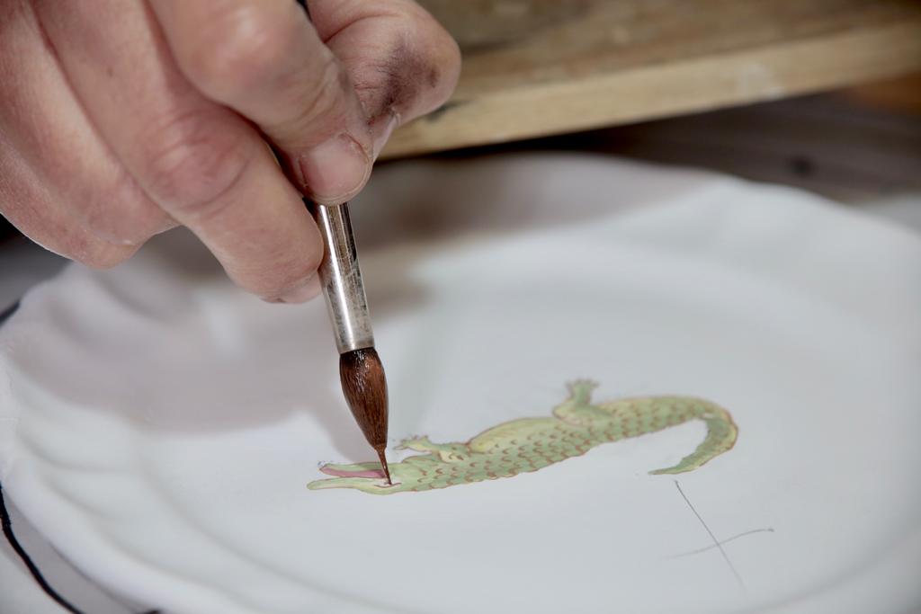 Artisan painting a crocodile side plate